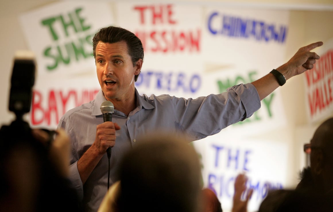 Gavin Newsom speaking into a microphone while pointing off-camera during his time as mayor of San Francisco.
