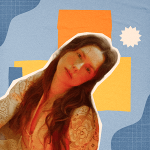 A woman with long dark hair, a short-sleeved shirt, and arm tattoos.